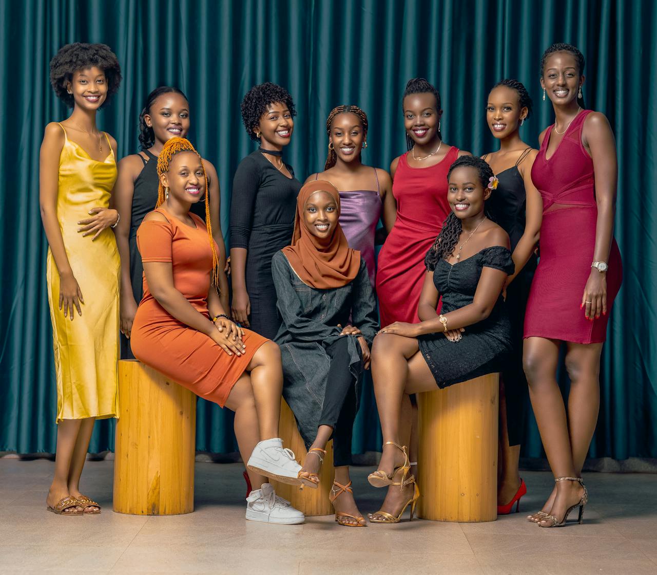 Home A stylish group of diverse women posing in elegant dresses indoors.